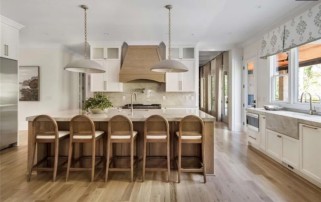 Elegant white kitchen with wood island and statement pendant lighting